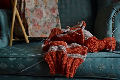 Close-up of wool and knitting needle on sofa