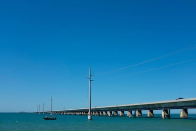 Bridge over sea against clear blue sky