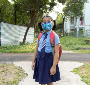 Portrait of a happy indian girl child student in blue school uniform bag and nose mask going school