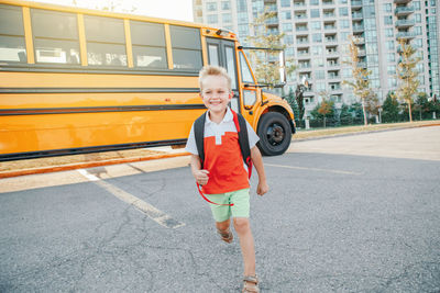 Smiling boy standing by bus