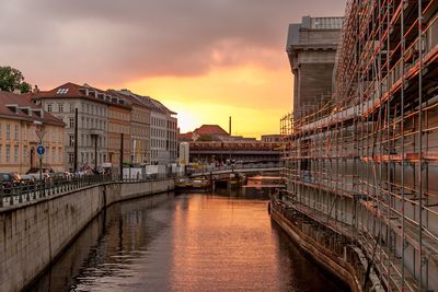 River in city against sky at sunset