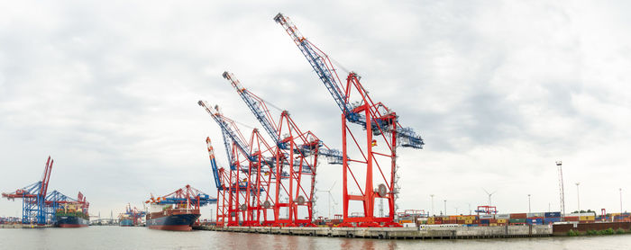 Cranes at commercial dock against sky