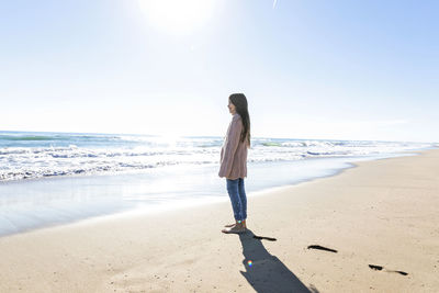Girl looking at horizon from beach on sunny day