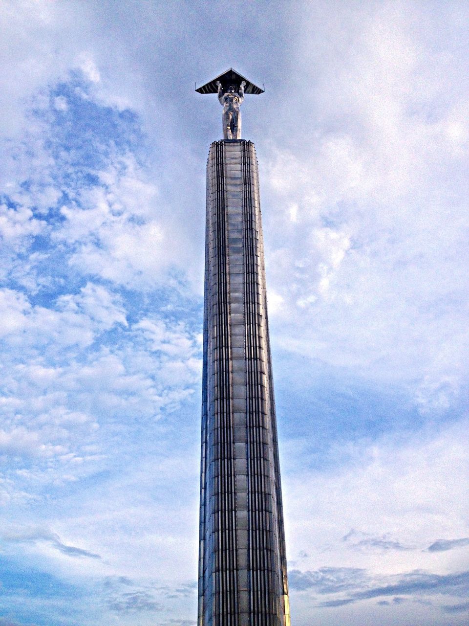 low angle view, sky, cloud - sky, built structure, architecture, tall - high, animal themes, cloudy, bird, famous place, cloud, flying, travel destinations, tower, day, travel, one animal, capital cities, building exterior, spread wings