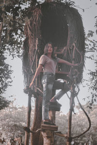 Portrait of man standing on tree trunk