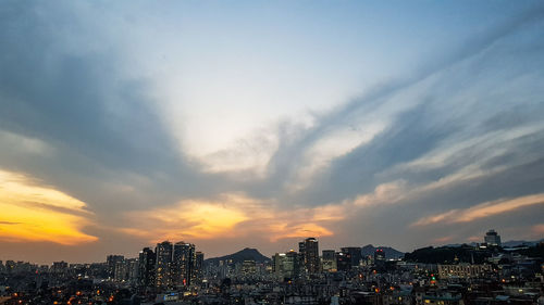 Buildings in city against sky during sunset