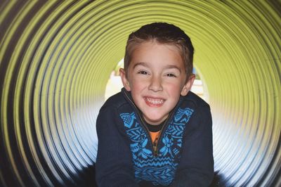 Portrait of happy boy lying in play equipment