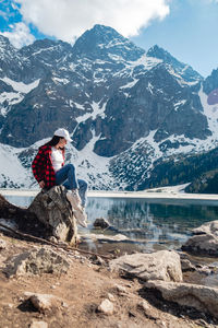 Rear view of woman sitting on rock at beach