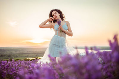 A beautiful young girl against the sunset and a beautiful sky in a lavender field. 