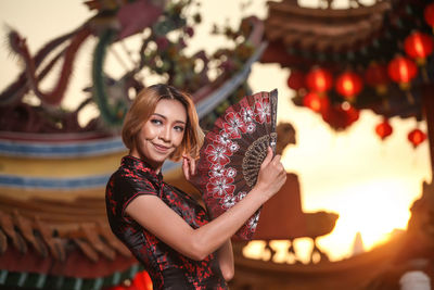 Portrait of smiling young woman standing against wall