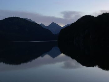 Reflection of silhouette trees in lake against sky