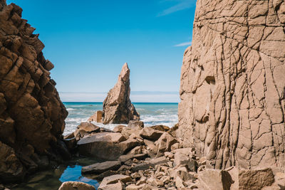 Rock formations at beach against blue sky