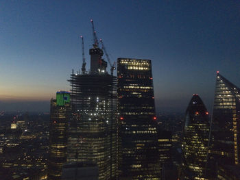 Illuminated buildings in city against sky at night