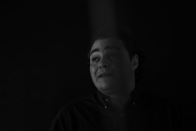Close-up portrait of smiling young man against black background