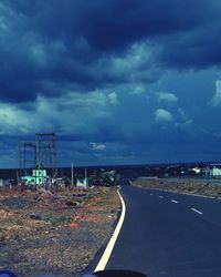 Road by city against sky at dusk