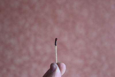 Close-up of fingers holding burning matchstick