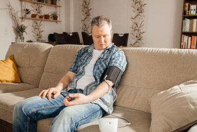 A man measures his blood pressure at home with a cuffed blood pressure monitor. health check at home