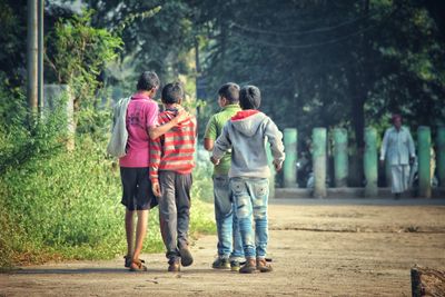 Rear view of boys walking on footpath