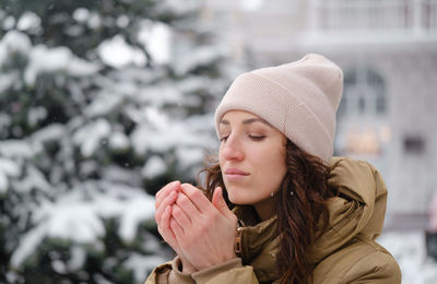 Happy middle age woman warming hands in the city outdoors. relaxed emotional person walking in