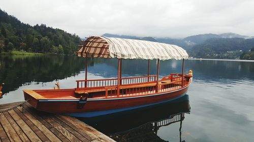 Boat moored on lake against sky