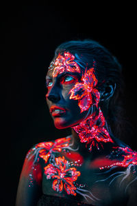 Young woman with paint on her body against black background