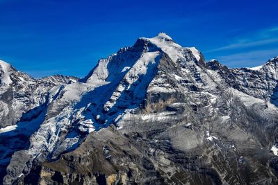Scenic view of snowcapped mountains against blue sky