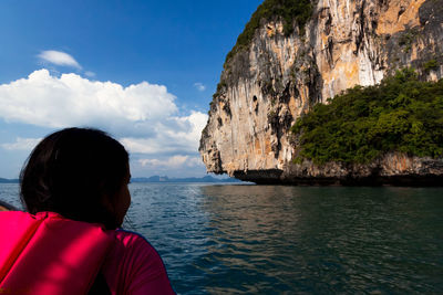 Rear view of woman looking at sea against rock formation