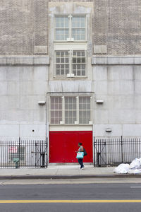 Man walking on sidewalk by building