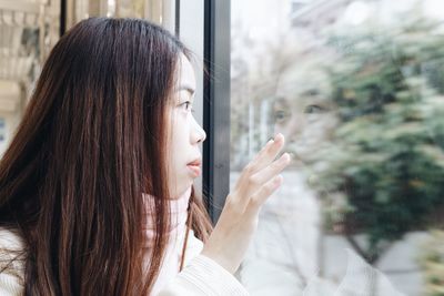 Portrait of woman looking through window