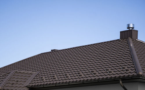 Low angle view of building roof against clear sky