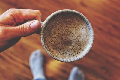 Cropped hand of person holding espresso at home