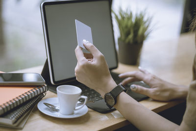 Midsection of man holding coffee cup on table