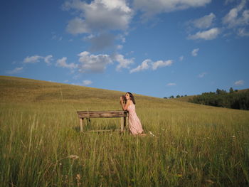 Rear view of woman standing on field against sky