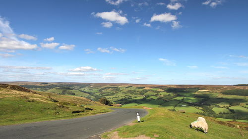 Road amidst landscape against blue sky