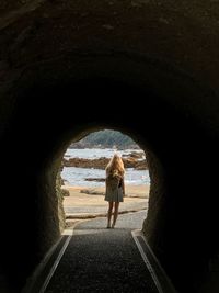 Rear view of woman standing in tunnel