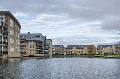 Buildings by river against sky