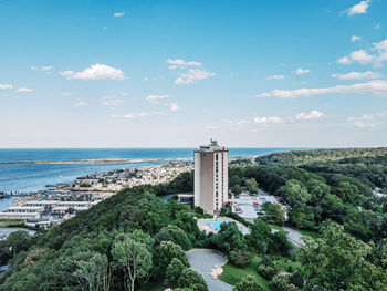 Lighthouse amidst sea and buildings against sky