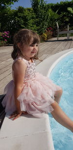 Smiling cute girl sitting on poolside