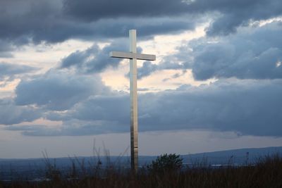 Cross on grass against sky