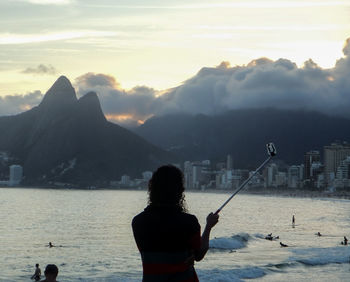 Rear view of man with woman standing in sea against mountains