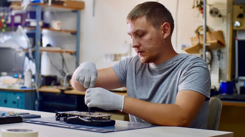 Man repairing computer equipment on table in workshop