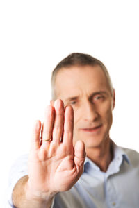 Portrait of man gesturing stop sign against white background