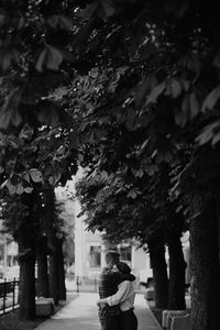 Rear view of woman walking on footpath amidst trees