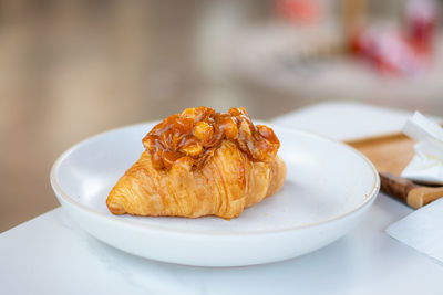 Croissant with macadamia nuts topping, homemade with white table background.