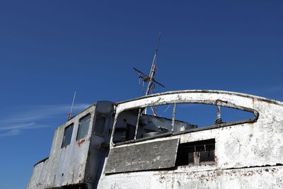 Low angle view of abandoned building against clear blue sky