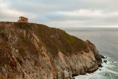 Scenic view of cliff by sea against sky