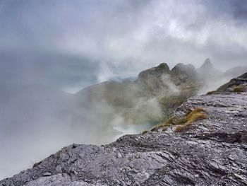 Smoke emitting from mountain against sky