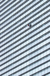 Low angle view of window washer working on modern building