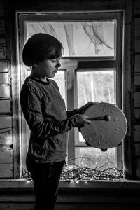 Side view of boy playing drum at home