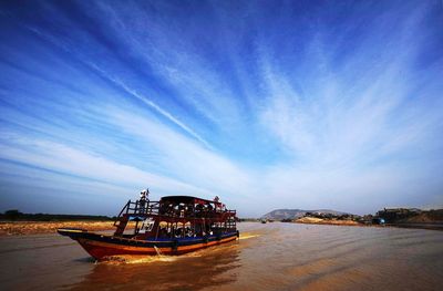 Boats in sea against cloudy sky